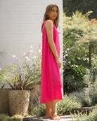 Woman in a bright pink dress standing in a garden setting.